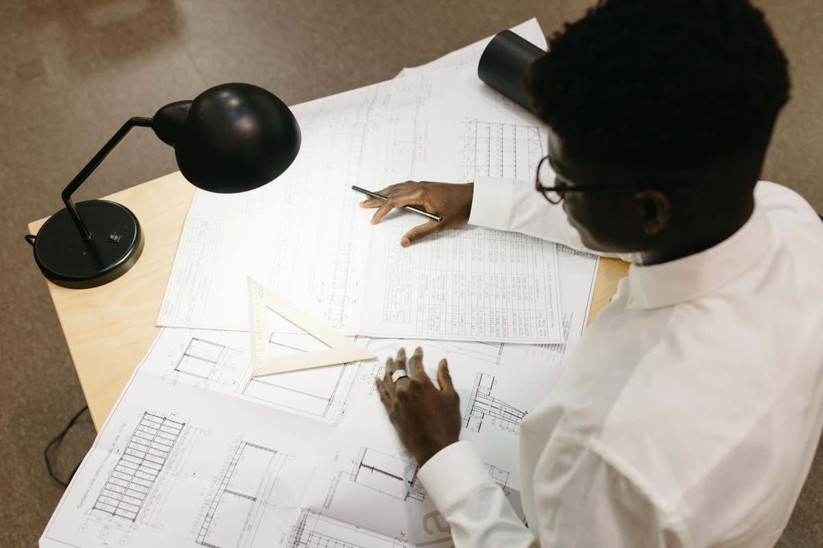 Top view of an architect reviewing building plans spread across a desk