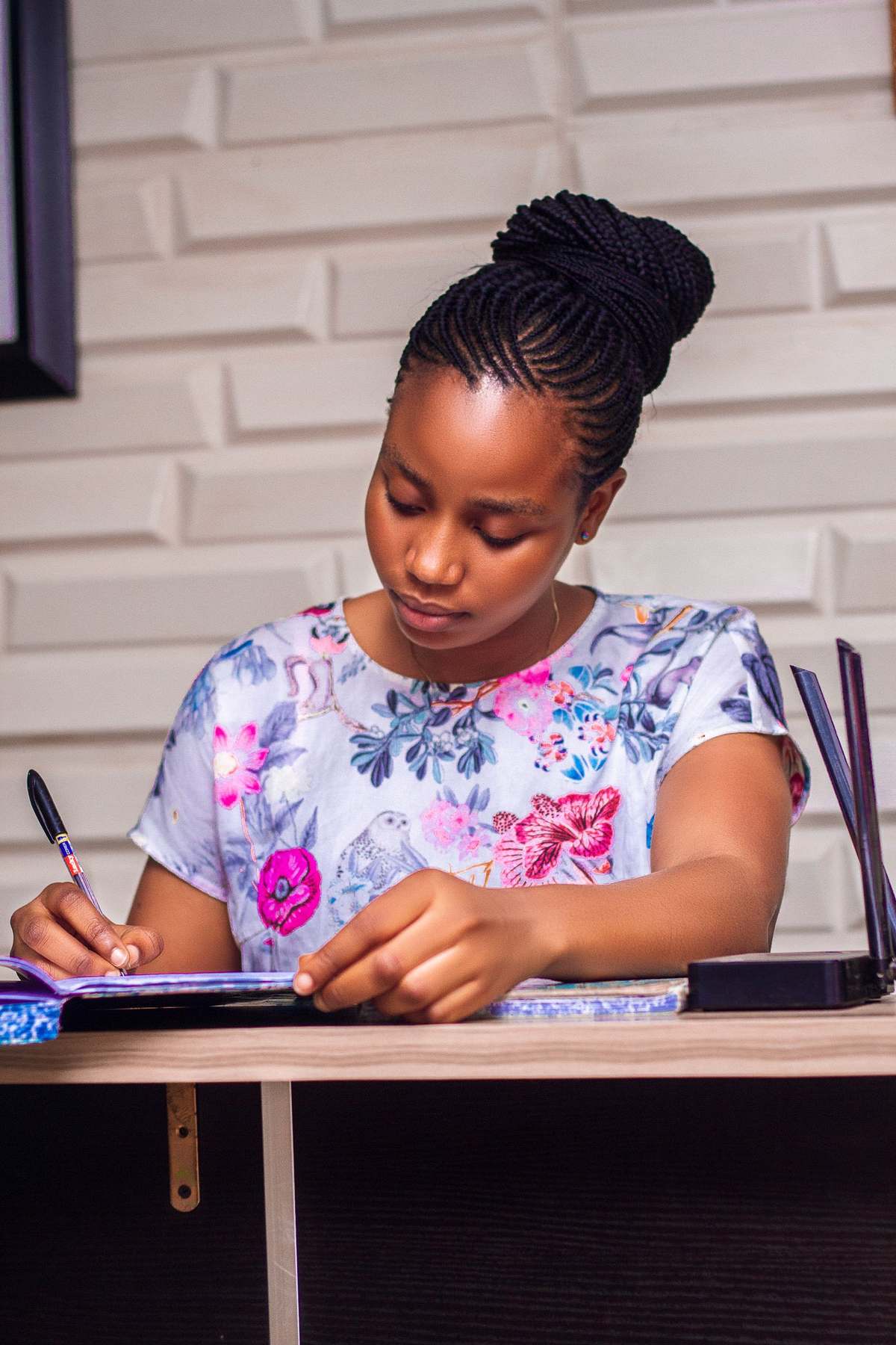 African woman with braided hair filling in an application form at her desk