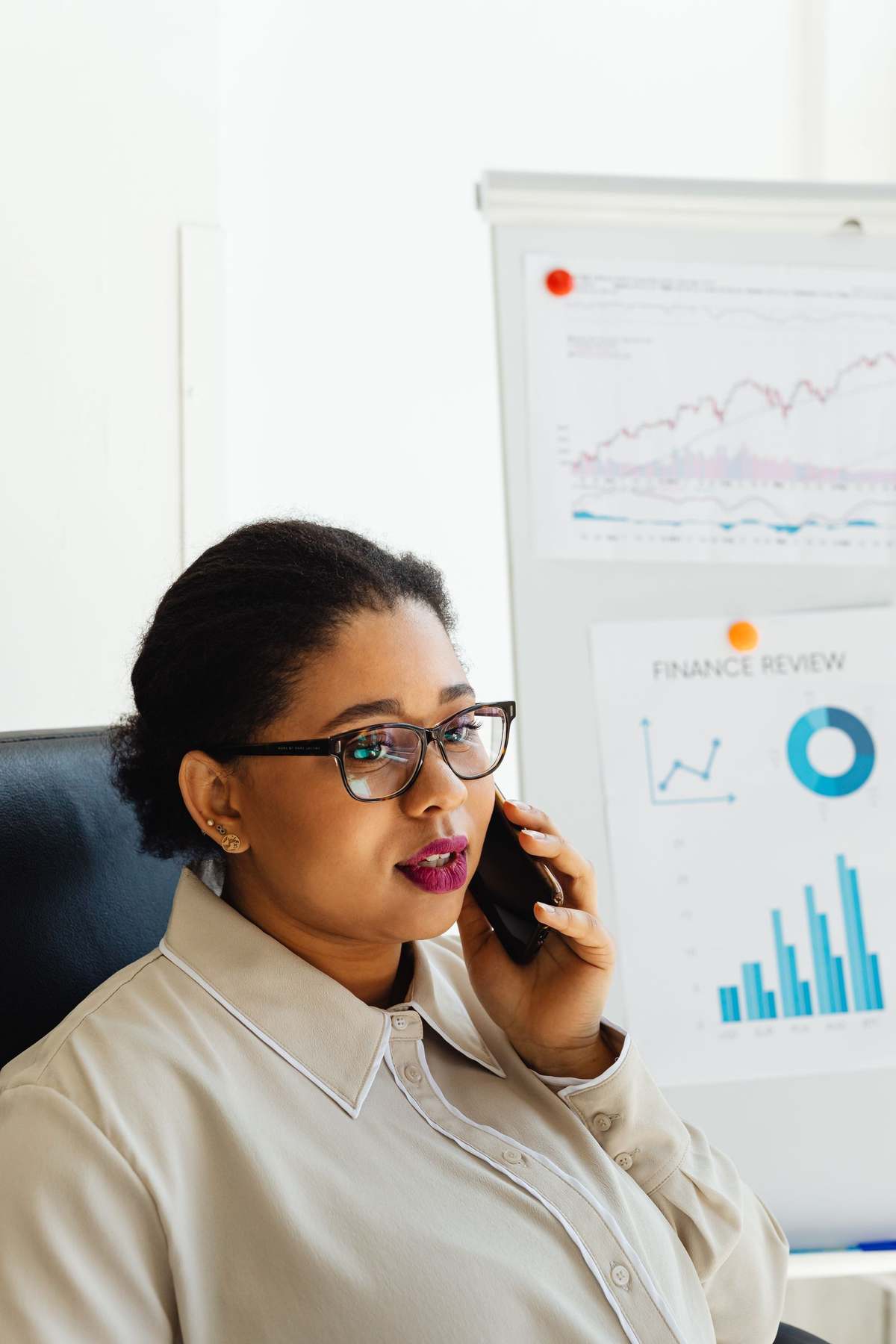 Professional woman on a phone call beside finance review charts