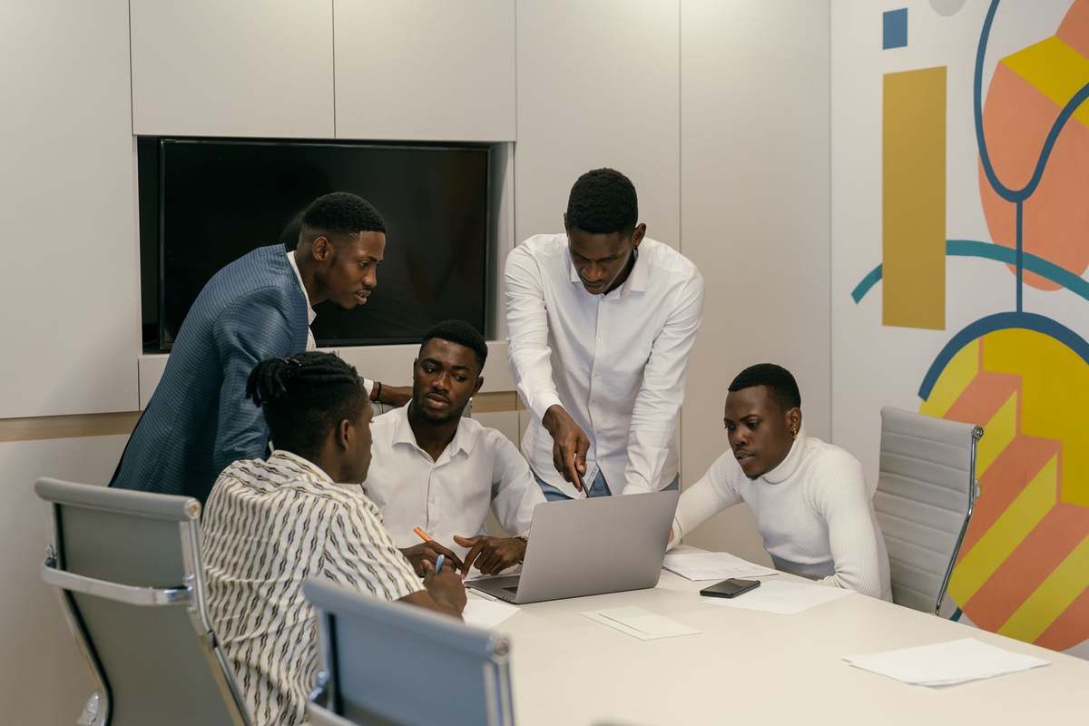 Team of young Black professionals working through a plan around a laptop